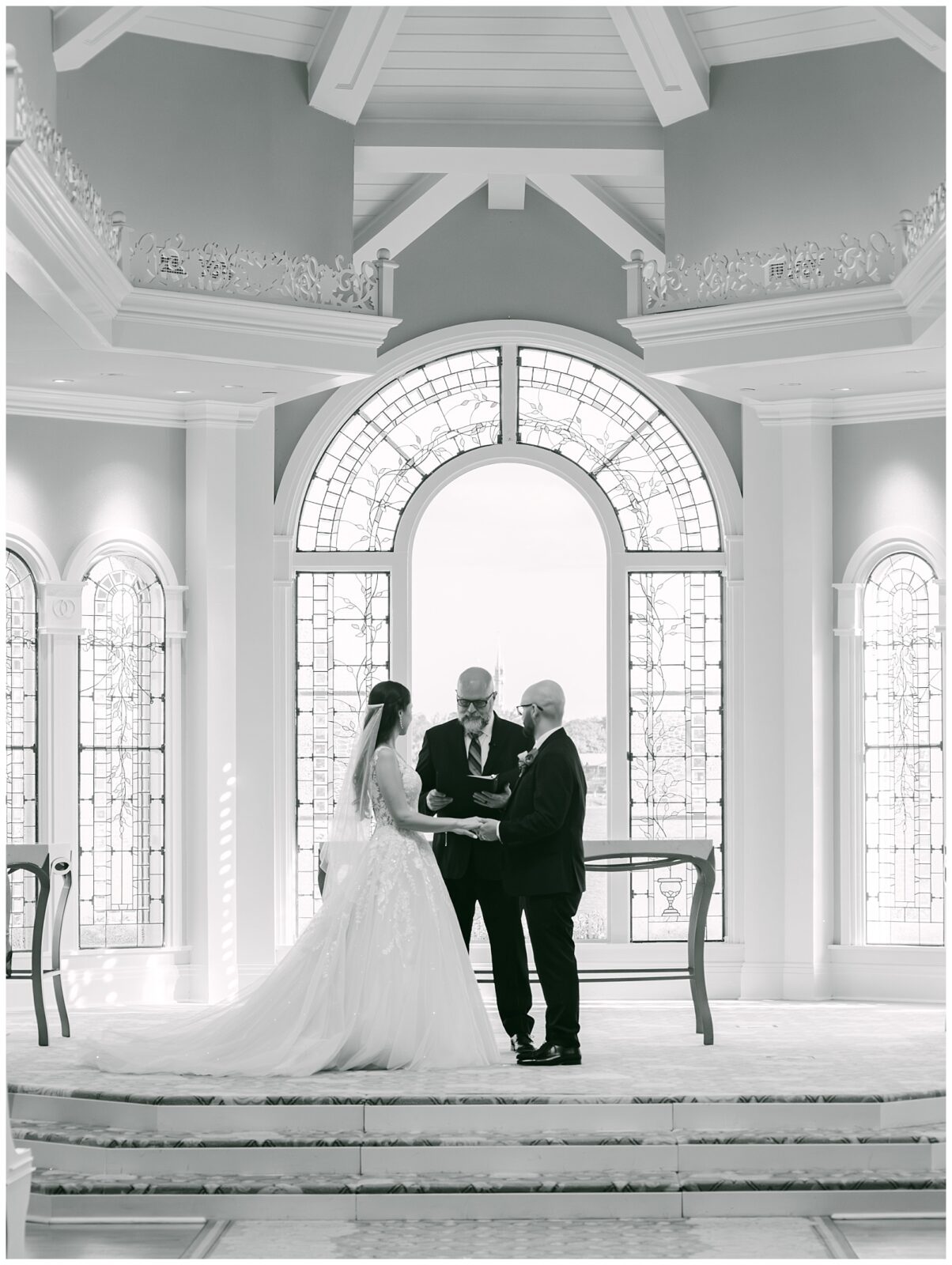 Black and white portrait of Pastor leading the bride and groom through their wedding ceremony. By Elizabeth Kane Photography in Orlando Florida