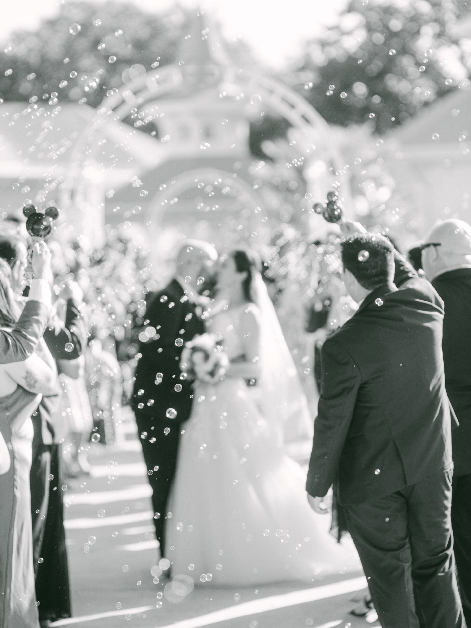 Joyful newlyweds making their way through a sea of bubbles as they exit the ceremony by Elizabeth Kane Photography Disney Destination Wedding Photographer Orlando Florida