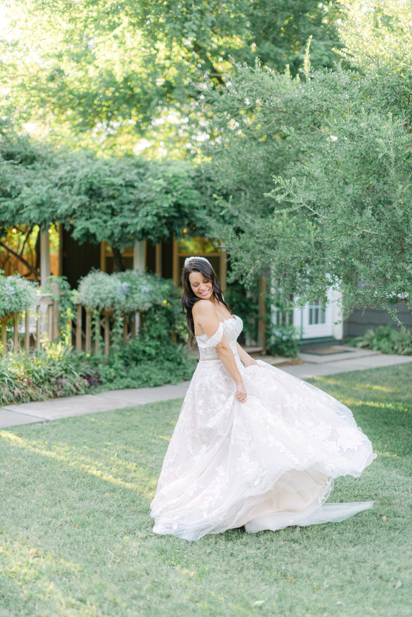 Bride twirling in an off-the-shoulder lace wedding gown during golden hour at a garden venue in Philadelphia, captured as part of a bespoke wedding photography experience focused on elegance, legacy, and timeless moments