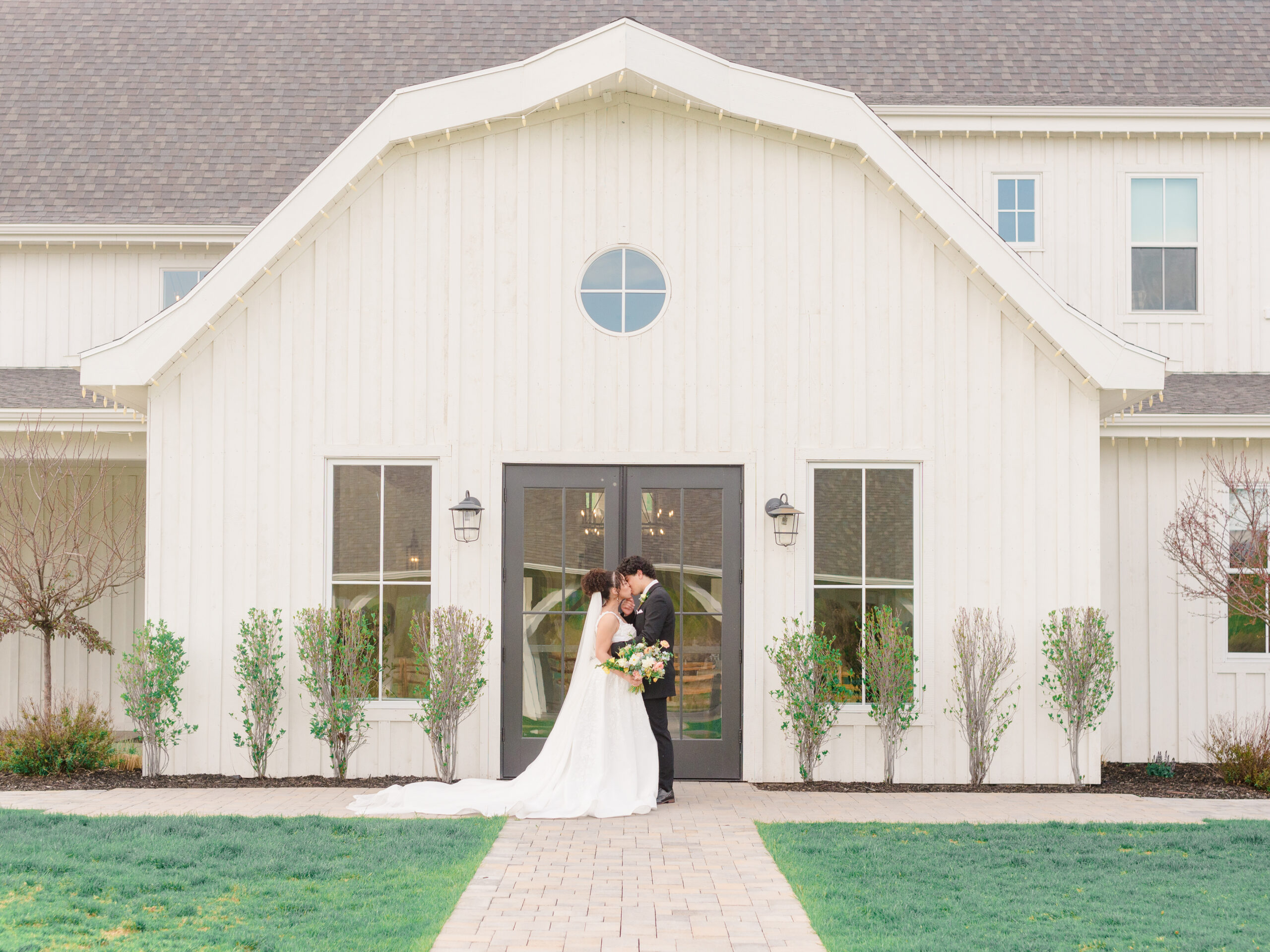 Bride and groom sharing a quiet moment in front of a modern white barn wedding venue, captured by a documentary wedding photographer in Philadelphia with soft, natural light.
