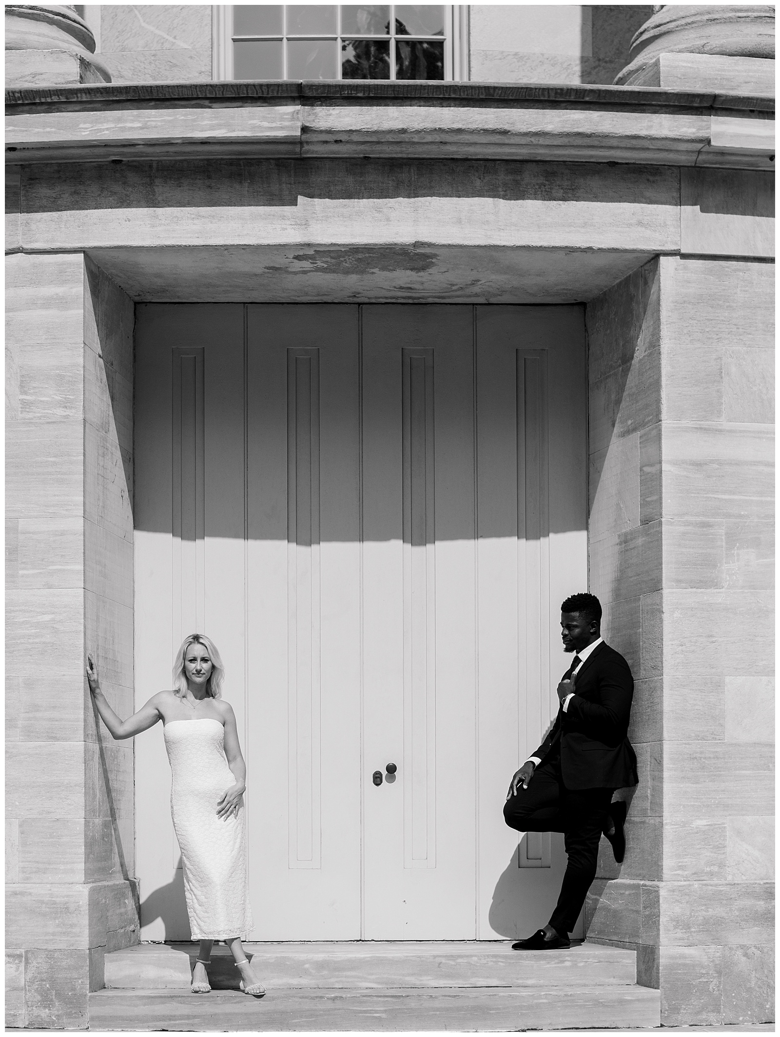 Black and white photo of engaged couple posing against historic architecture in Old City Philadelphia engagement session
