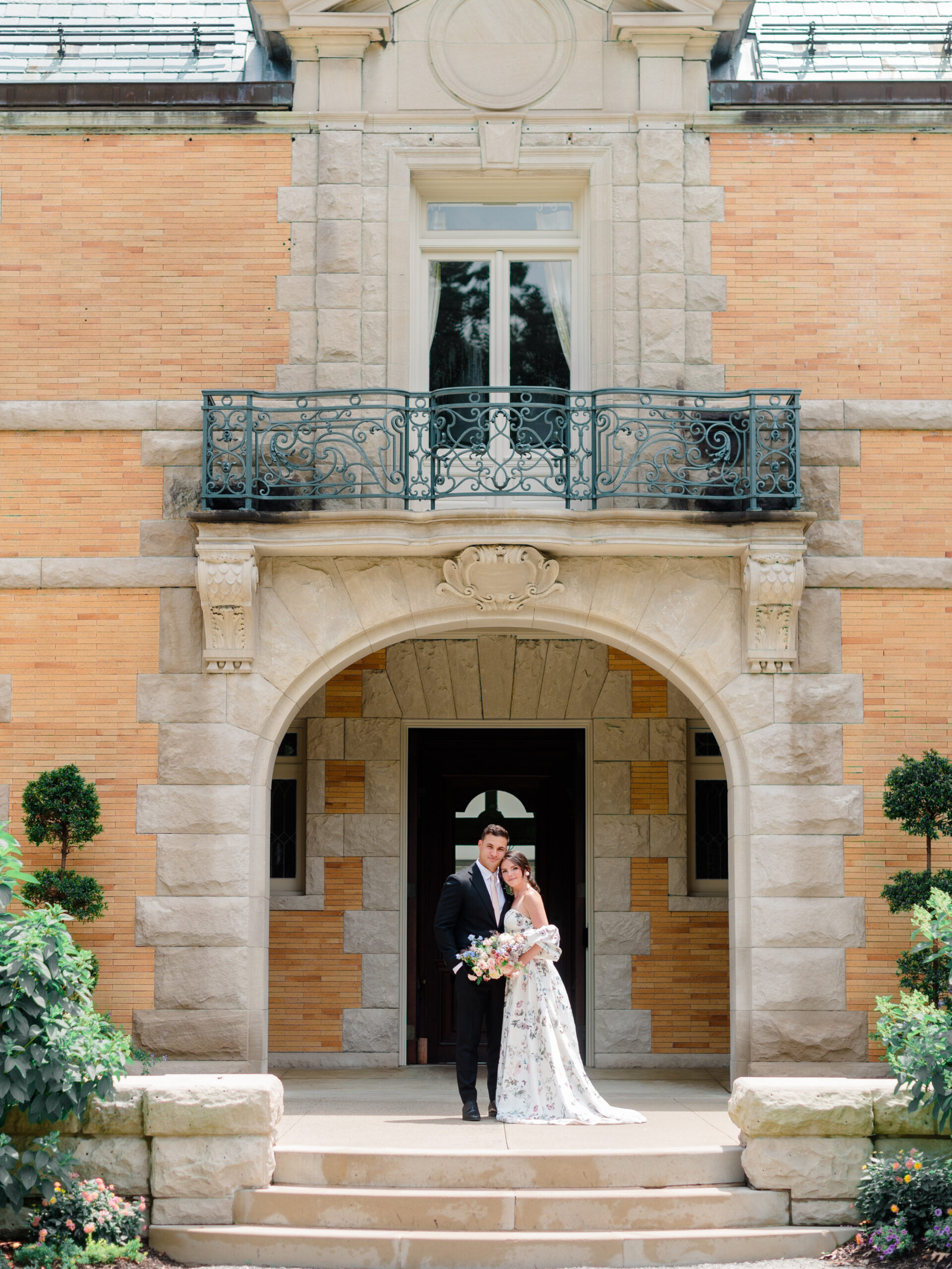 Elegant couple standing beneath the stone archway of Cairnwood Estate in Bryn Athyn, captured by Elizabeth Kane Photography during a historic estate wedding editorial shoot. The timeless architecture and romantic setting highlight the charm of a Philadelphia estate wedding steeped in tradition and elegance.