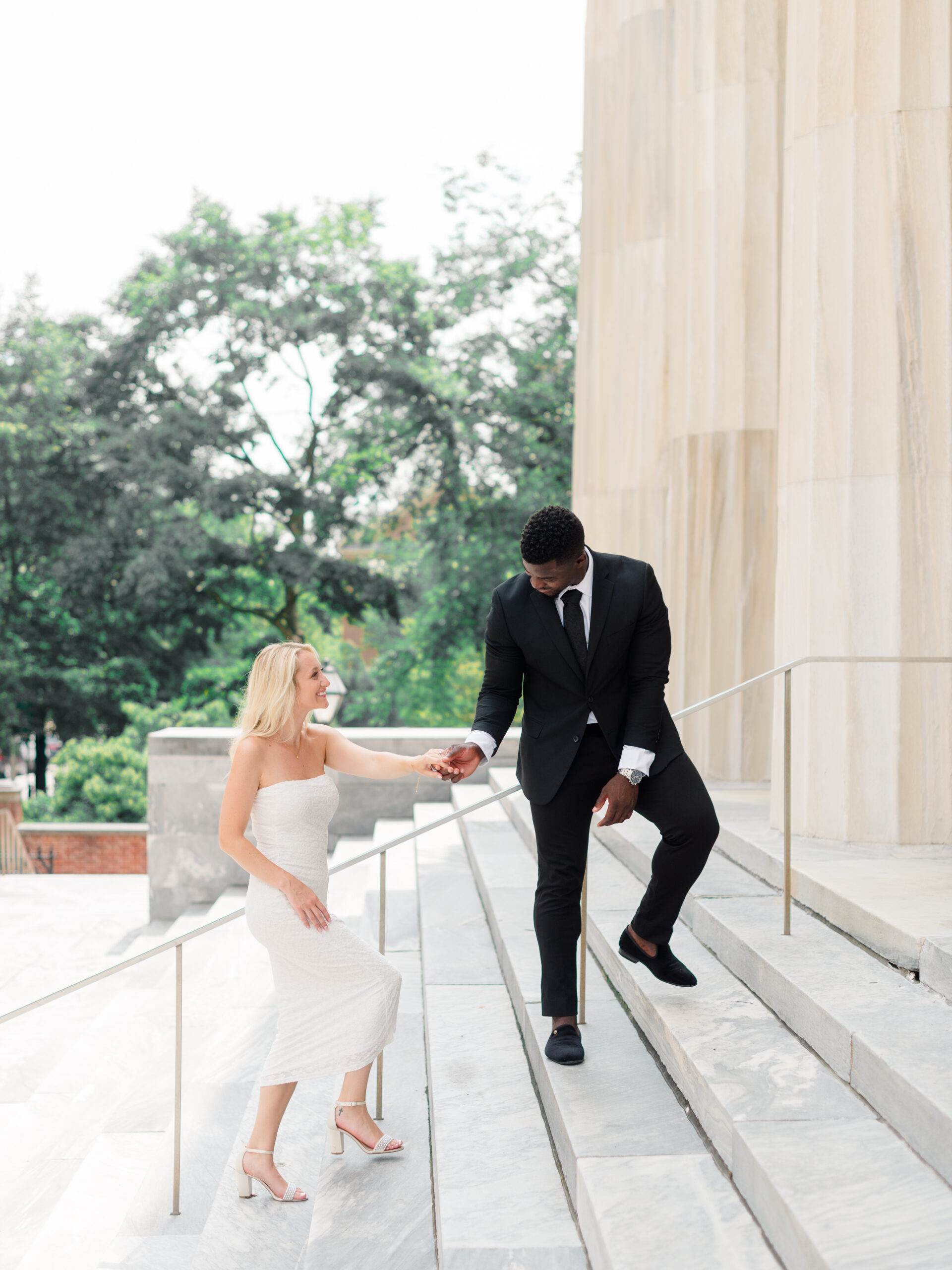 Engagement session at the 2nd Bank of the United States in Old City Philadelphia, with a couple on marble steps holding hands, an elegant reminder that planning for hidden costs of wedding photography ensures timeless portraits in historic locations.