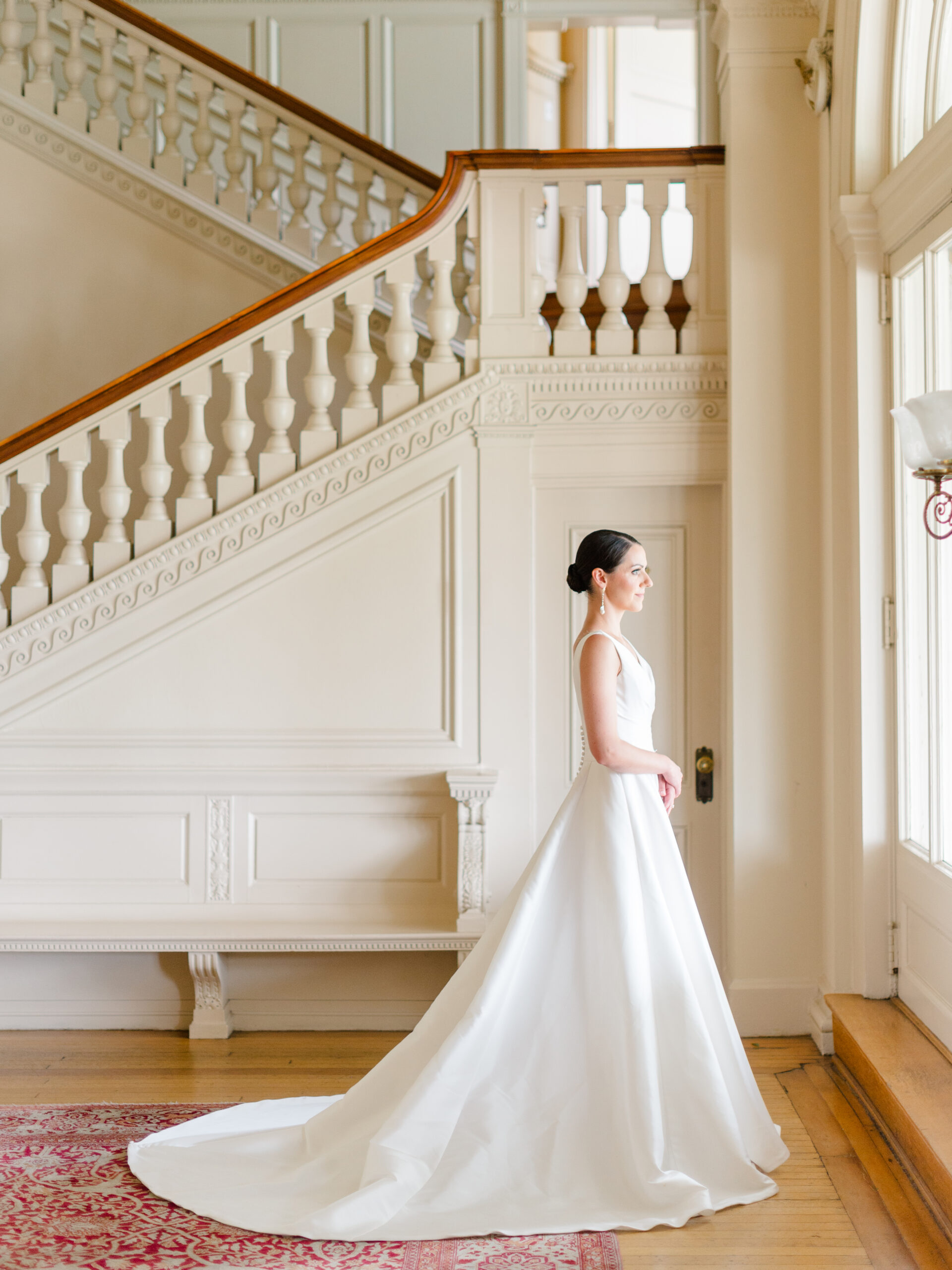 Bridal portrait inside Cairnwood Estate wedding venue in Bryn Athyn, Pennsylvania, featuring a bride in a classic gown near the historic staircase.