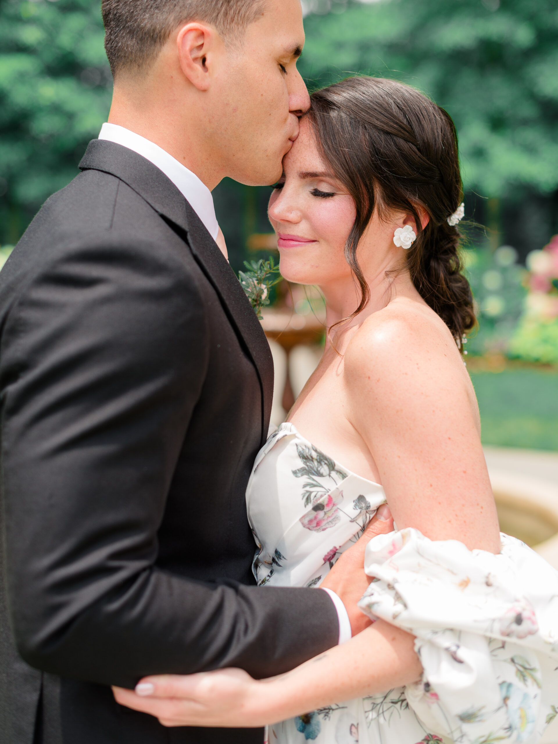 Romantic wedding photo at Cairnwood Estate wedding venue in Bryn Athyn, Pennsylvania, capturing a groom kissing the bride’s forehead.
