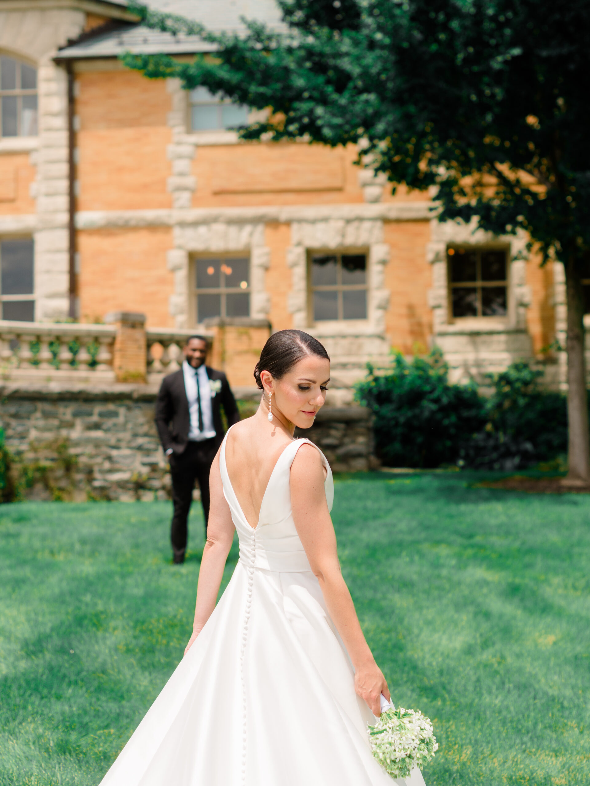 Wedding portrait at Cairnwood Estate wedding venue in Bryn Athyn, Pennsylvania, featuring a bride on the estate grounds with the groom behind her.