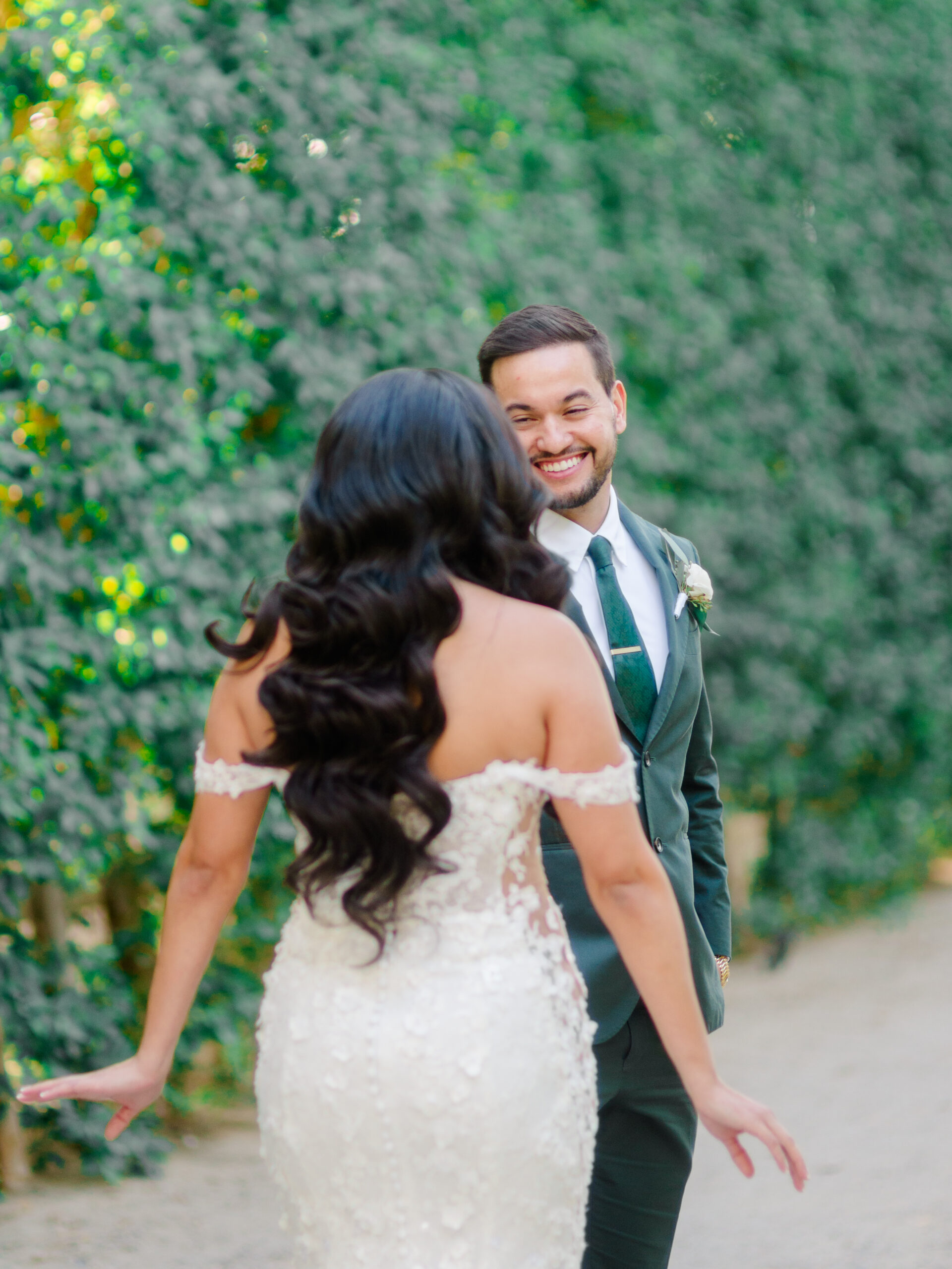Boutique full-service wedding photography capturing an emotional first look between bride and groom during an intimate outdoor wedding moment surrounded by greenery.