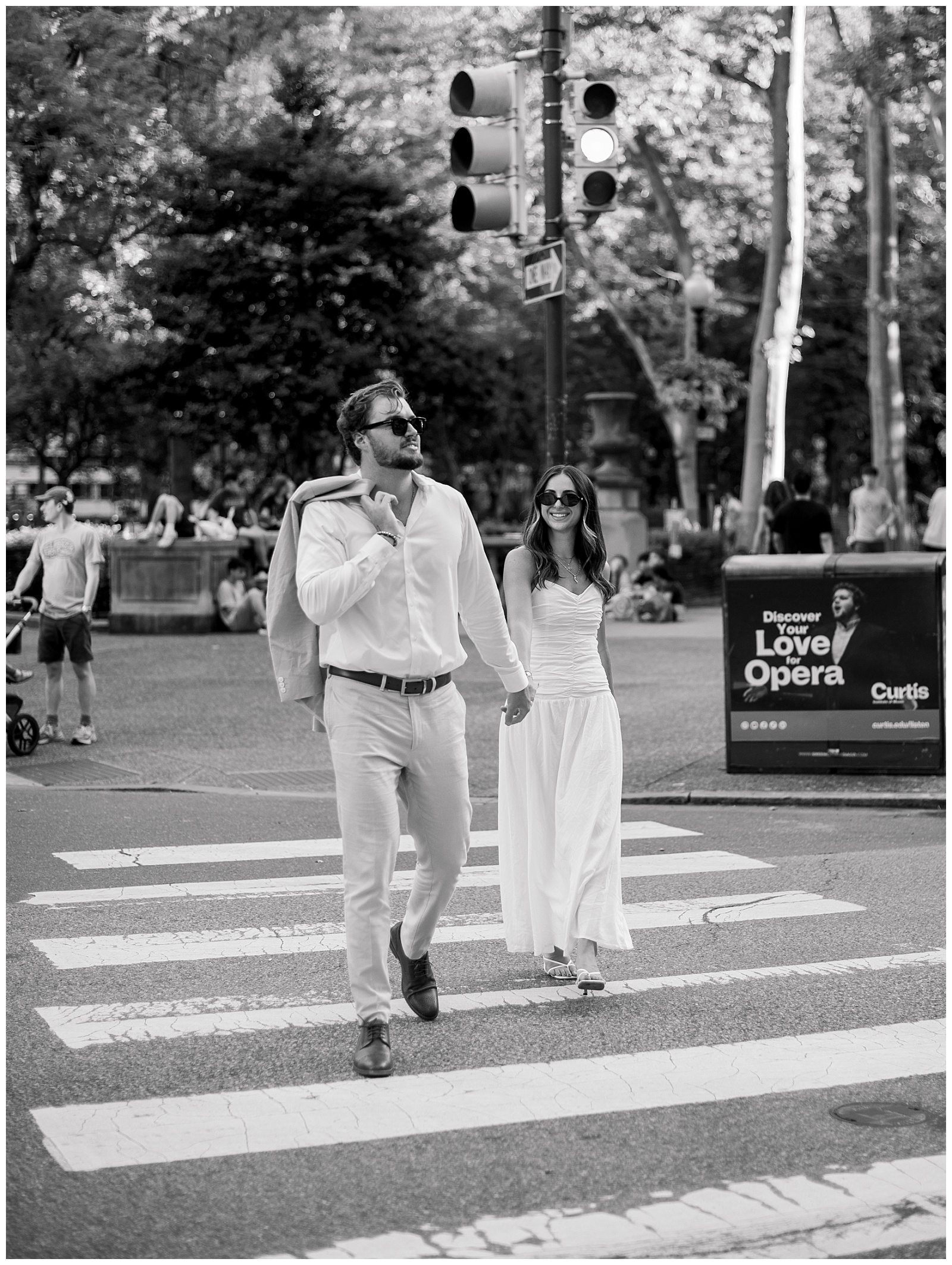 Editorial black and white moment from a Philadelphia engagement session as a couple walks through Rittenhouse Square