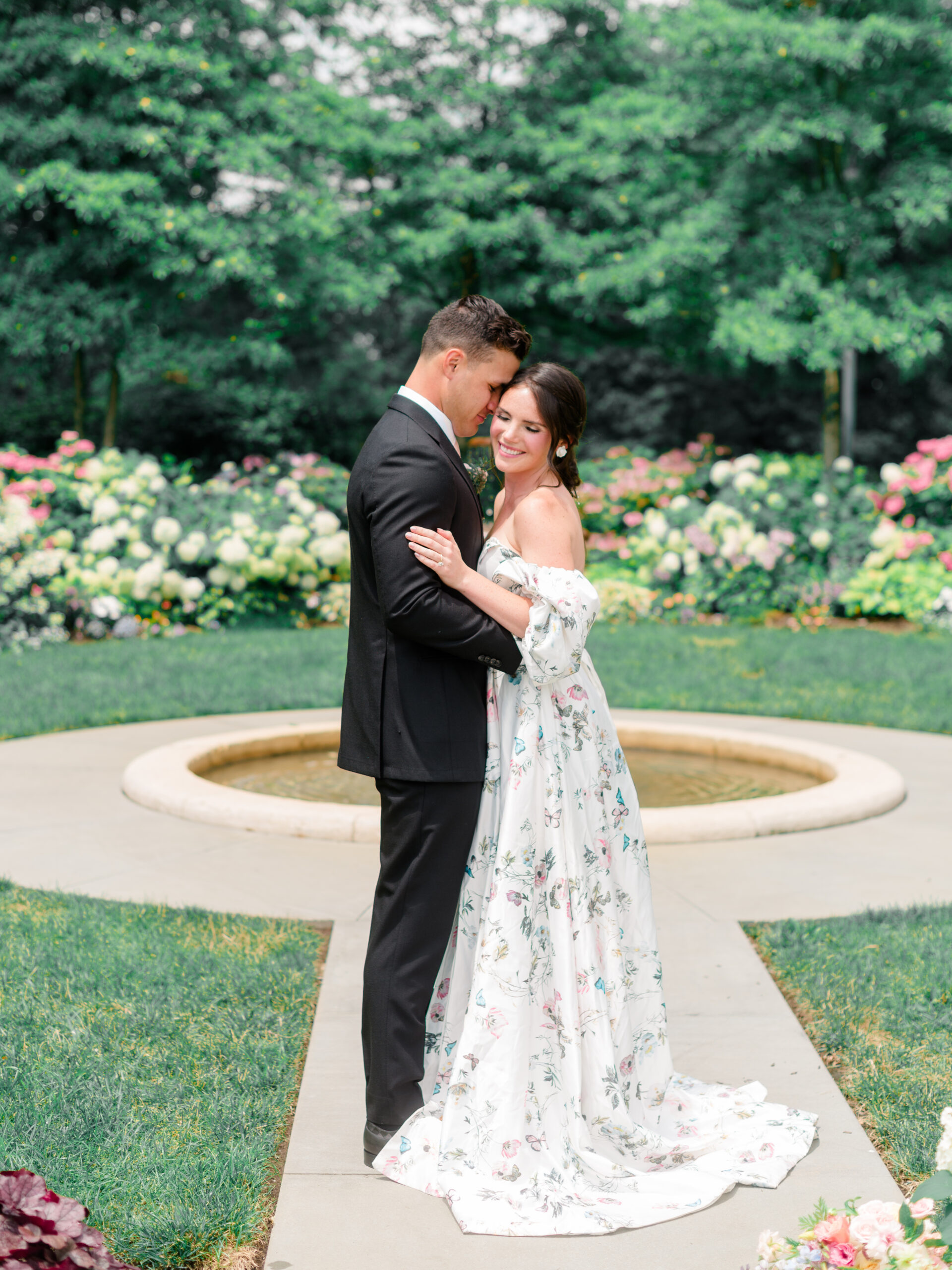 Couple embracing in the formal gardens at Cairnwood Estate in Bryn Athyn, photographed in a refined luxury Philadelphia wedding photography style.