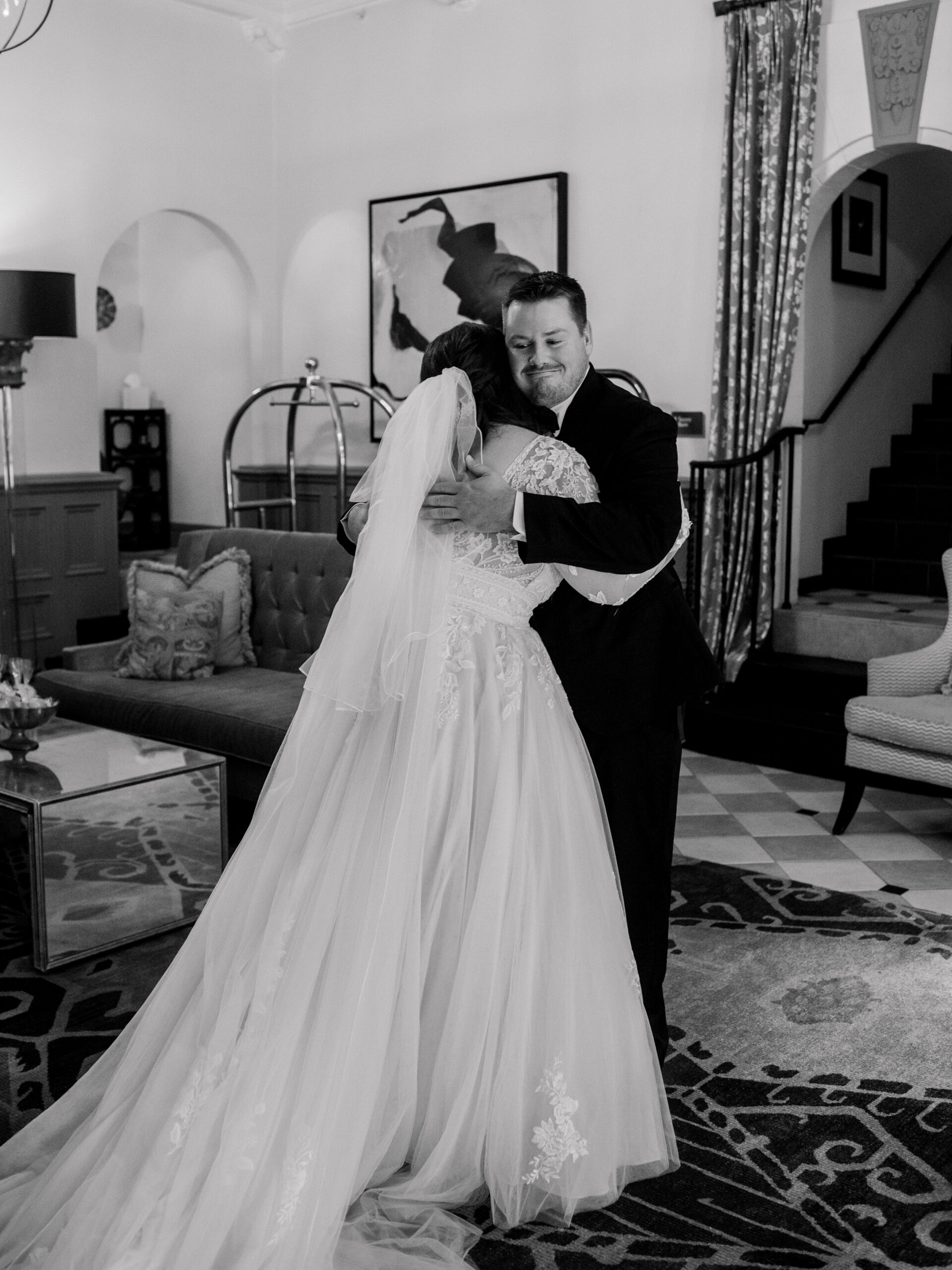 Emotional black and white portrait of bride and groom sharing a quiet embrace indoors, photographed by a full-service wedding photographer in Philadelphia.